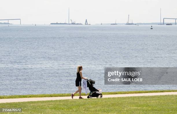 Person pushes a stroller near the collapsed span of the Francis Scott Key Bridge in Baltimore, Maryland, June 12 following the reopening of the...