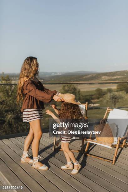 family laughing and having fun on summer hotel terrace. stylish clothing on mom with daughter. - fashionable mom stock pictures, royalty-free photos & images