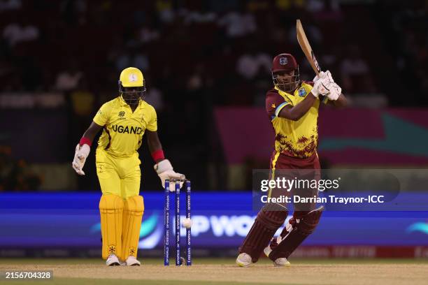 Johnson Charles of West Indies bats as Simon Ssesazi of Uganda looks on during the ICC Men's T20 Cricket World Cup West Indies & USA 2024 match...