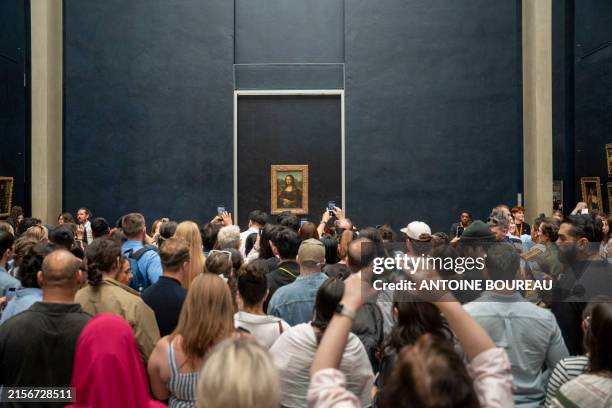 Crowd of tourists with their phones in hand, taking photos of Leonardo da Vinci's Mona Lisa inside the Louvre Museum in Paris, France on 7 June 2024.