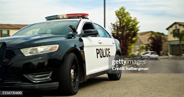 locked off shot of side of police car on suburban road - police car stock pictures, royalty-free photos & images