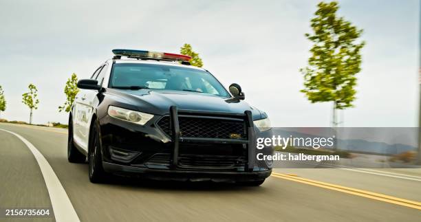 wide shot of police car on urban road in california - police car stock pictures, royalty-free photos & images