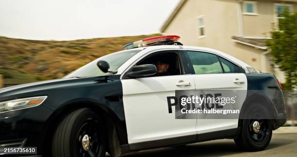 police officer in squad car with suburban home in background - police car stock pictures, royalty-free photos & images
