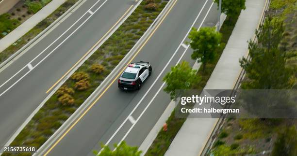 drone shot of police car on urban road - police car stock pictures, royalty-free photos & images