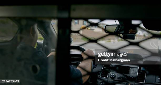 behind-the-bars detainee pov of police officer driving squad car - detainee stock pictures, royalty-free photos & images