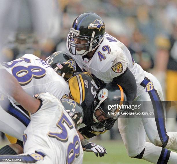 Defensive backs Chad Williams and James Trapp and linebacker Peter Boulware of the Baltimore Ravens tackle running back Chris Fuamatu-Ma'afala of the...