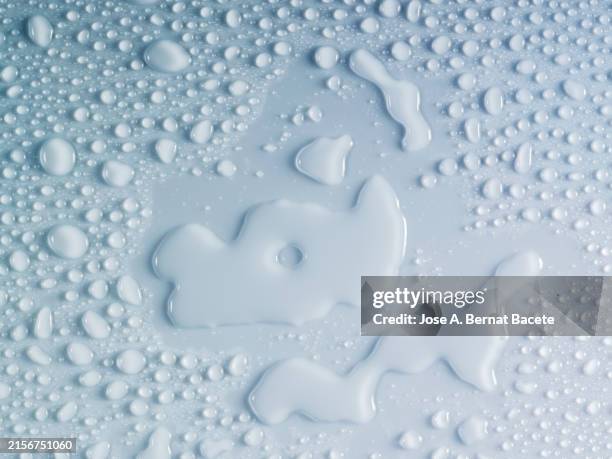 full frame of small drops and splashes of water on a soft blue background. - goutte de pluie photos et images de collection