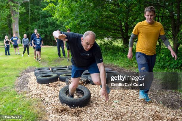 Liberal Democrat leader Ed Davey trips on a tyre as he takes part in an assault course with local parliamentary candidate Mike Martin during a visit...
