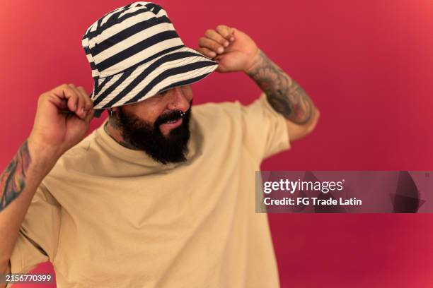 mature man on a studio shot with red background - bucket hat stock pictures, royalty-free photos & images