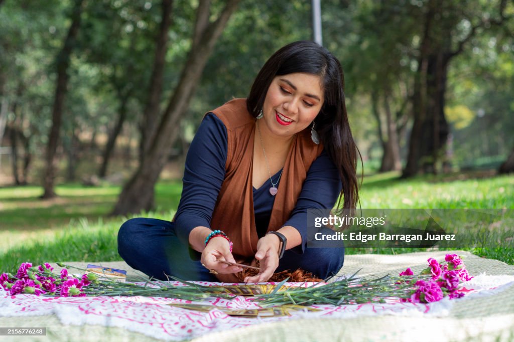 Woman smiling while reading tarot cards sitting in the park