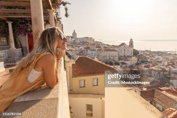woman relishing the view of lisbon's alfama district - provincie lissabon stockfoto's en -beelden
