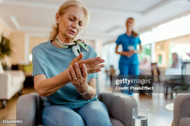 ältere patientin leidet in altersheim unter betäubenden schmerzen in der hand - gelenkrheumatismus stock-fotos und bilder