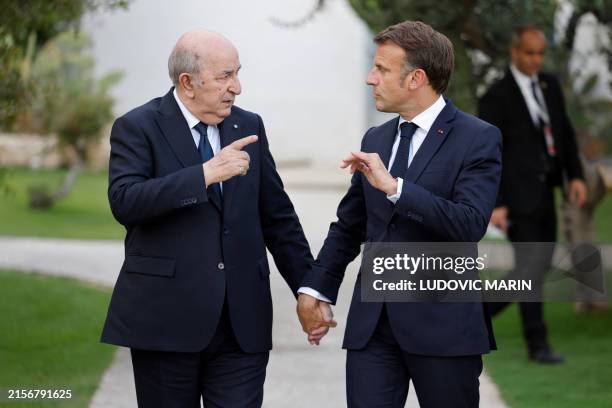 France's President Emmanuel Macron and Algeria's President Abdelmadjid Tebboune gesture towards each other as they attend the G7 Summit hosted by...