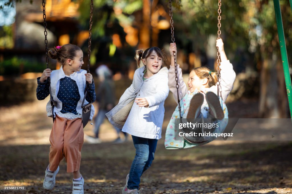 Glückliche kleine Mädchen in den Hängematten des Spielplatzes