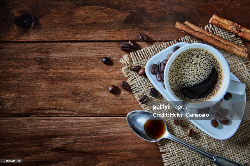 Cup of espresso with coffee beans on rustic wooden table