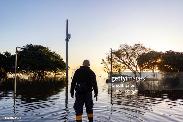hombre de mediana edad caminando en una zona inundada al final de la tarde - inundación fotografías e imágenes de stock