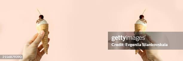 Womans Hand Holding An Ice Cream Cone On A Pink Background High-Res Stock Photo