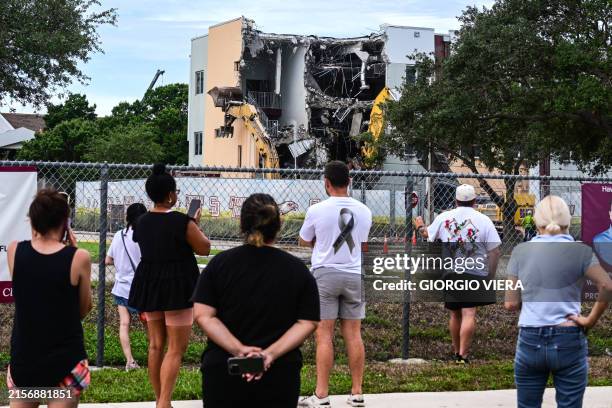 People watch as crews begin to demolish the building where seventeen people were killed during the 2018 mass shooting at Marjory Stoneman Douglas...