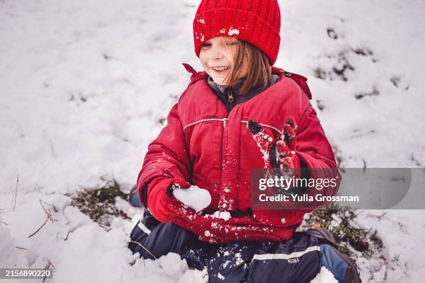 a cute girl in a red cap makes a snowball. - snowball stock pictures, royalty-free photos & images