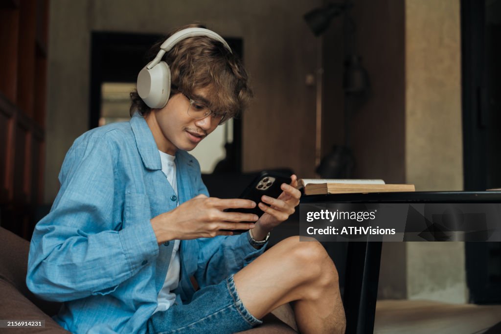 Gen Z man listening podcast while travel at hostel