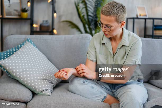 femme adulte moyenne se grattant la peau à la maison - irritation cutanée photos et images de collection