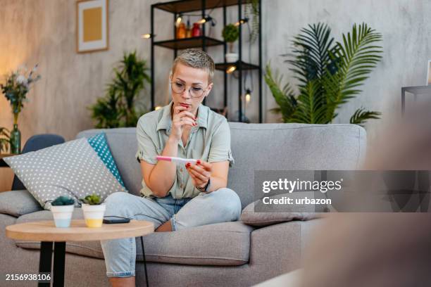 disappointed mid-adult woman taking a pregnancy test at home - ovulation stock pictures, royalty-free photos & images