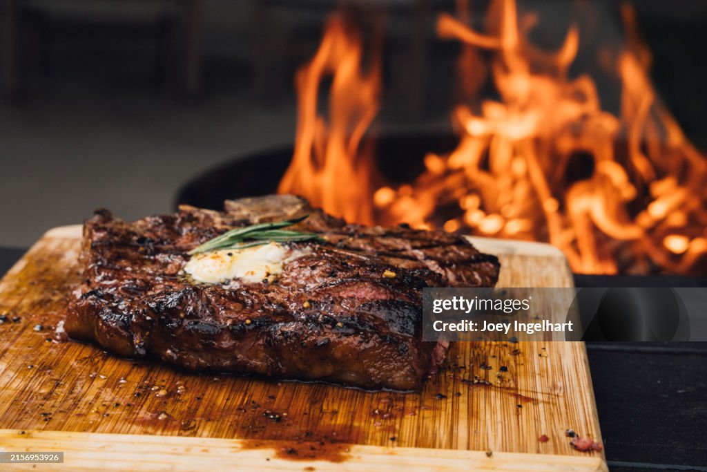 Ein perfekt gegartes T-Bone-Steak mit Butter, Gewürzen und Rosmarin, zubereitet auf einem Holzkohlegrill