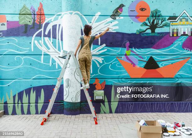mid adult iranian woman artist painting mural on public stairway wall - mural stock pictures, royalty-free photos & images