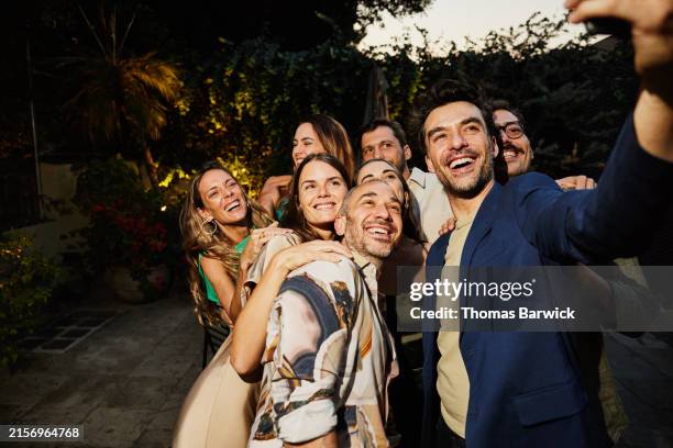 medium shot smiling friends taking selfie during rooftop dinner party - luxury dinner party stock pictures, royalty-free photos & images