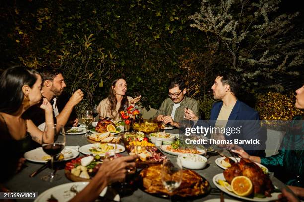 wide shot friends in discussion during rooftop dinner party - jantar-com-convidados - fotografias e filmes do acervo