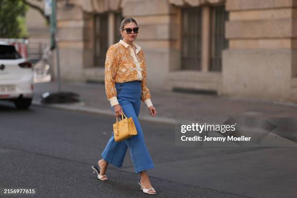 Aline Kaplan is seen wearing large sunglasses with beige, brown and black pattern from Tibi; chunky golden hoop earrings; several golden necklaces; a...