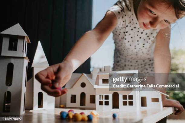 a little girl plays with a cardboard village - spielzeughaus stock-fotos und bilder