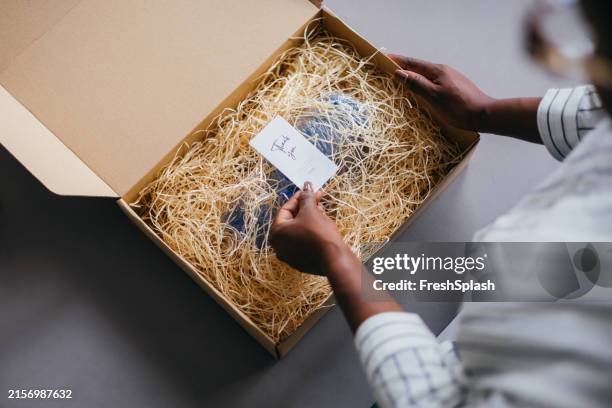 mujer paquete de apertura con tarjeta de agradecimiento en caja - paquete fotografías e imágenes de stock