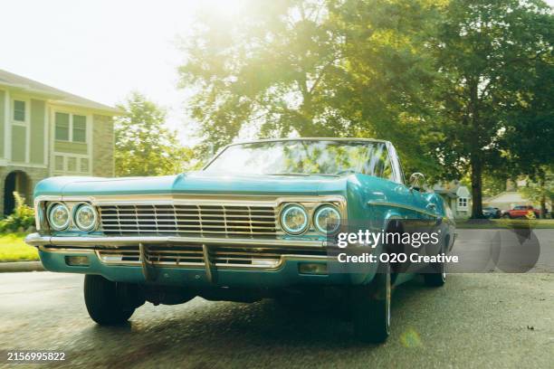 homme dans une voiture décapotable lowrider roulant dans un quartier - voiture-ancienne photos et images de collection