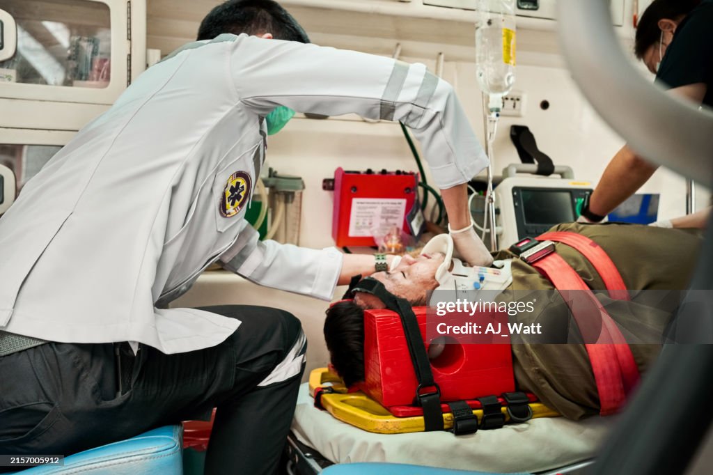 Paramedic team strapping an injured patient to a stretcher in the ambulance