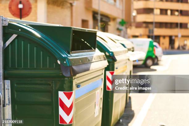 side view of a group of green metal garbage containers on city street in a row without people. - müllcontainer stock-fotos und bilder