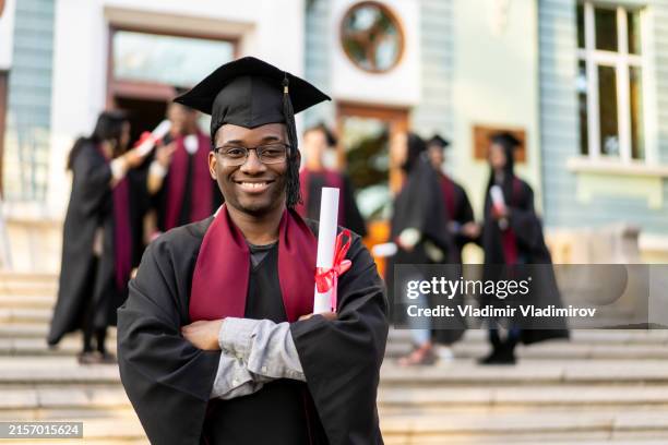 an alumnus holding his degree - traje académico imagens e fotografias de stock