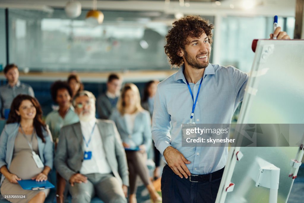 Happy male CEO drawing plans during presentation in board room.