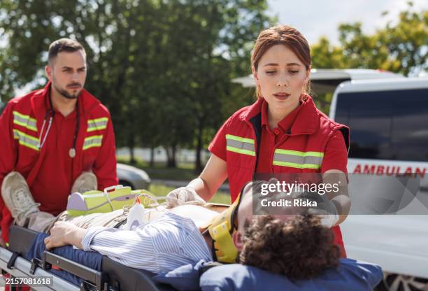 paramedics providing emergency medical care to injured patient outdoors - international red cross and red crescent movement stock pictures, royalty-free photos & images