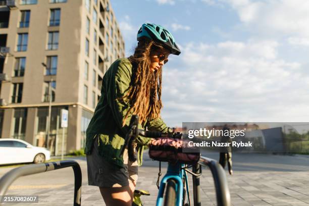 stylish woman locking her bike in urban setting - vintage padlock stock pictures, royalty-free photos & images