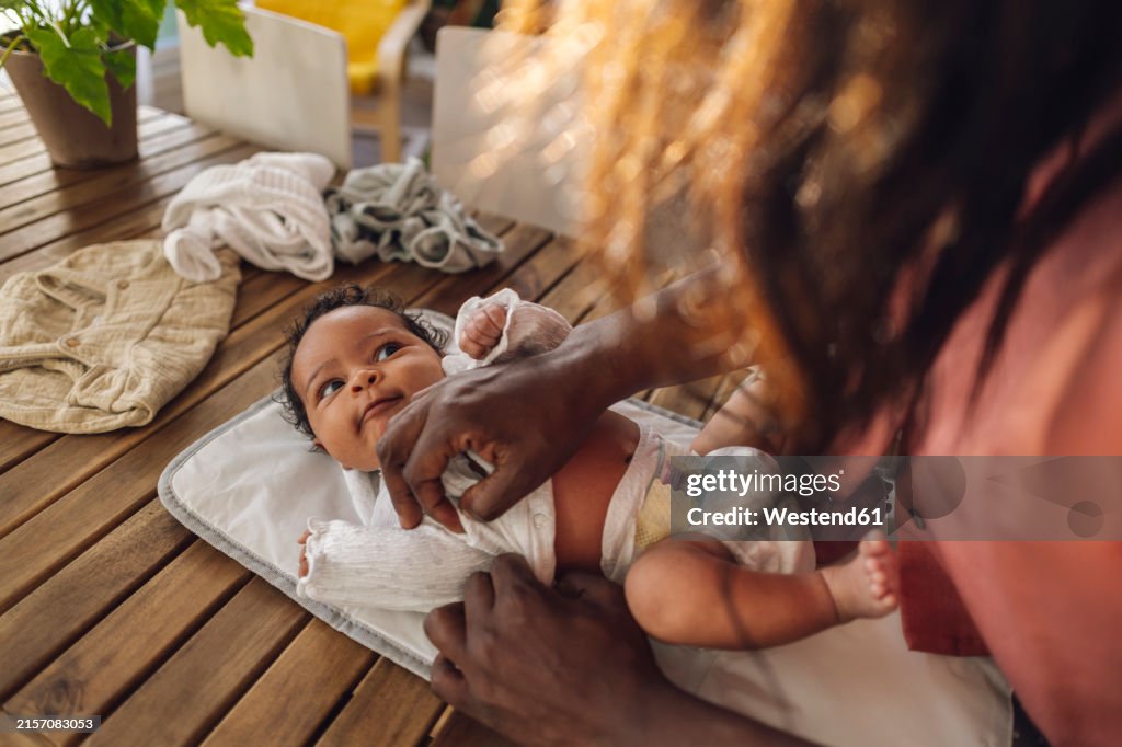 Mother changing daughter's clothes at home