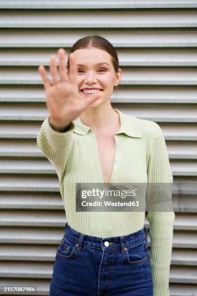 smiling woman showing stop gesture near wall - stop gesture stock pictures, royalty-free photos & images