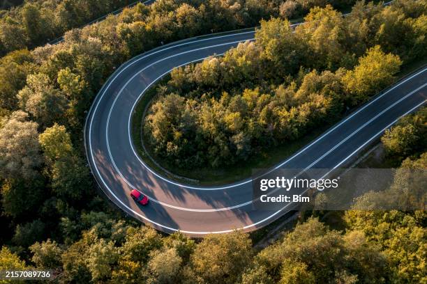 red car on a winding road - driving empty road stock pictures, royalty-free photos & images