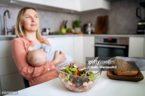 fresh food on dining table with mother breastfeeding toddler son in kitchen - breastfeeding stock pictures, royalty-free photos & images