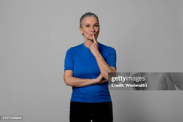 senior woman with finger on lips - woman with finger on lips stock pictures, royalty-free photos & images