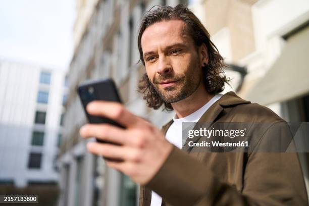 handsome mature man using smart phone - foco diferencial imagens e fotografias de stock