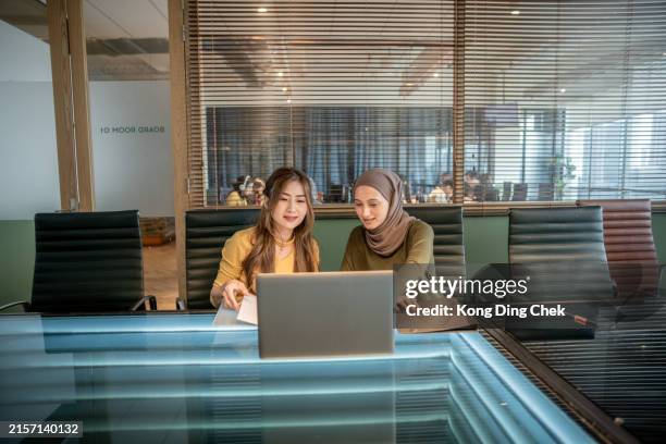 2 asian businesswomen discussing strategy and ideas at office - malaysian people stock pictures, royalty-free photos & images