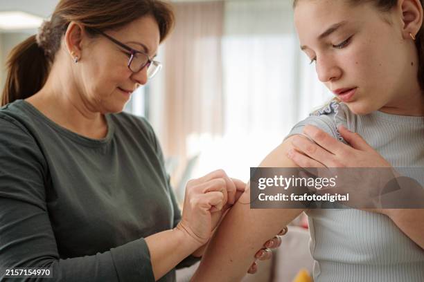 mother placing transdermal patch on her daughter's arm - transdermal patch stock pictures, royalty-free photos & images