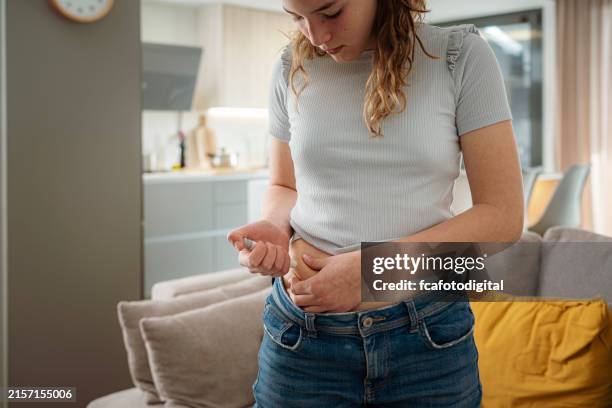 teenager-mädchen injiziert insulin in die magenhaut - blutzuckerspiegel stock-fotos und bilder