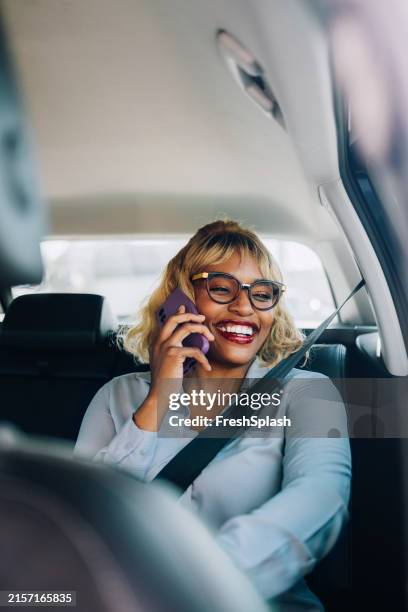 woman smiling while talking on phone in a car - blue suit stock pictures, royalty-free photos & images